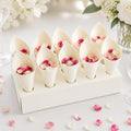 White paper cones filled with pink and white flower petals on a light surface.